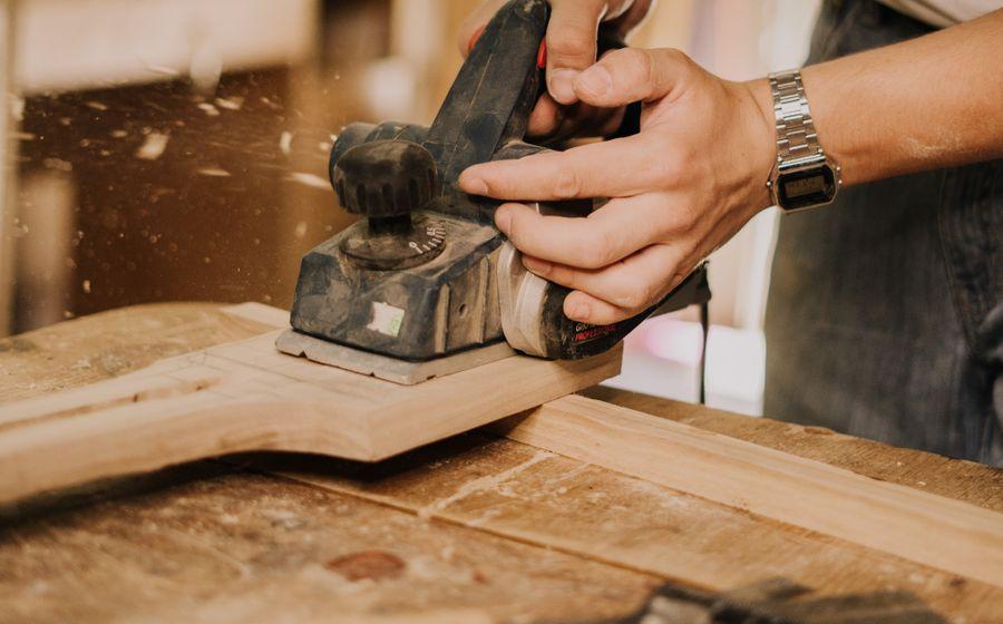 Close view of a woodworker sanding a piece of timber
